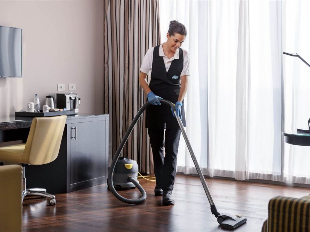 Cleaner vacuuming a room.