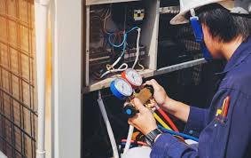 Two technicians work on a furnace system in a utility room.